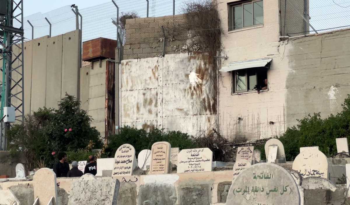 An Israeli occupation soldier threatens the PI delegation at gunpoint for visiting a local cemetery. 